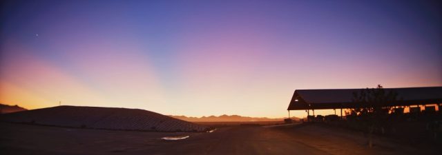 Vivid orange and purple sunset sky over the Shamrock Farms dairy buildings and Arizona landscape, captured during branded documentary production by NewLeaf Production Group
